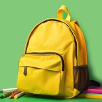 Yellow backpack, School bag on green background. AI generative.