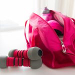 sport, fitness, healthy lifestyle and objects concept - close up of female sports stuff in bag and dumbbells